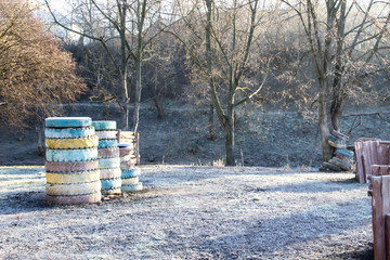 Paintball field for playing. Winter days in the park. A place with colorful wheels and trees