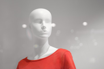 White mannequin in a red T-shirt on a grey background.