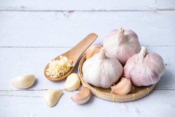Garlic, sliced garlic, garlic bulbs with garlic cloves in  basket place  on white color vintage wooden  background.