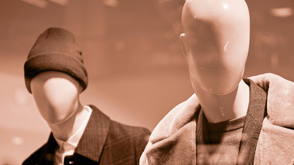 Two mannequins dressed in warm clothes in sepia colors.