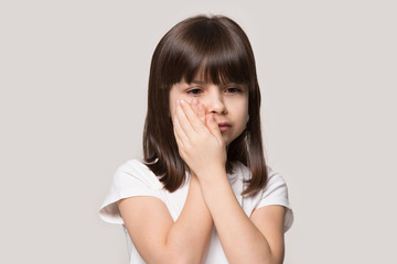 Upset charming six years old girl suffering from teething ache.