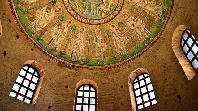 Ravenna, Italy, December 2019. Baptistery of the Aryans. Tilt movement footage towards the magnificent mosaics of the vault. From the red brick walls we move on to the colorful mosaic.