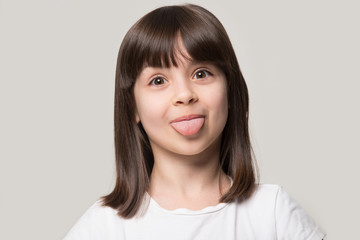Close up head shot portrait happy little girl showing tongue.
