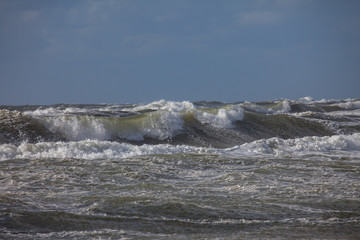 Waves of the north sea with white spindrift in front of a blue sky