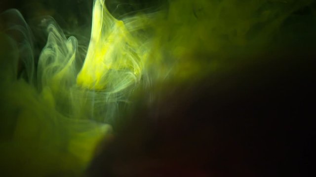 Real Shot Color Paint Drops In Water In Slow Motion. Ink Swirling. Color Ink Dropped In Water On Black Background. Cloud Of Silky Ink In Water Isolated.