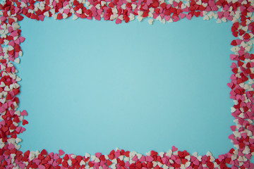 Rectangular frame with small multicolored hearts on a blue background, Valentine's day concept. Postcard.