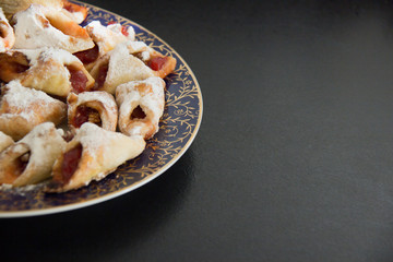 blue plate with homemade cookies with sugar powder on a black surface