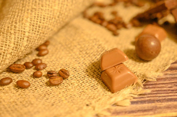 Chocolates and coffee beans on a background of rough homespun fabric. Close up.