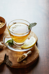 Cup of tea with lemon, natural ginger and ground ginger on a wooden board. Copy space design