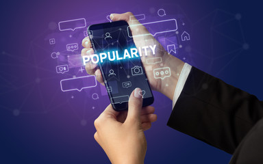 Female hand typing on smartphone with POPULARITY inscription, social media concept