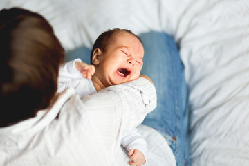 Woman holding a crying child. Mother comforts her little son or daughter.