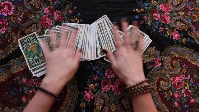 occultism tarot cards shuffling hands with rings and bracelets on it and floral traditional ornament on background