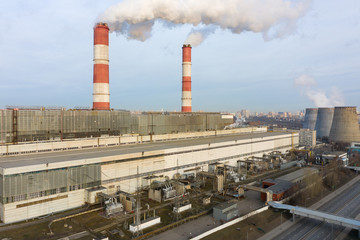 power plant pipes and cooling towers on the background of the panorama of the winter city against...