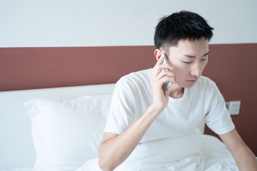 Attractive young man make a phone call on his bed