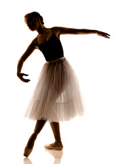 Silhouette of young beautiful ballerina in white tutu and pointe shoes doing dancing pose