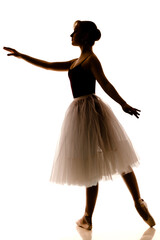 Silhouette of young beautiful ballerina in white tutu and pointe shoes doing dancing pose © YouraPechkin