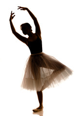 Silhouette of young beautiful ballerina in white tutu and pointe shoes doing dancing pose © YouraPechkin
