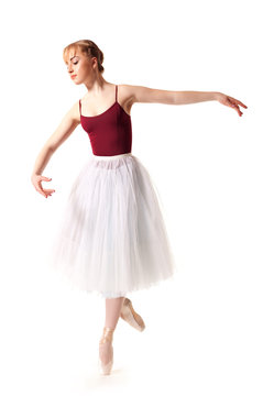 Young beautiful ballerina in white tutu and pointe shoes doing dancing pose