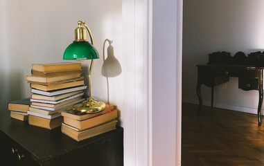 A stack of the old books and a vintage green lamp