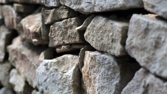 the camera moves past a wall of wild stone, slow motion