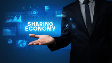 Hand of Businessman holding SHARING ECONOMY inscription, business success concept