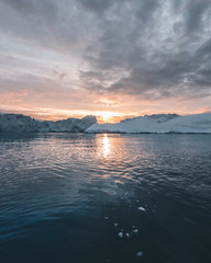 Arctic nature landscape with icebergs in Greenland icefjord with midnight sun sunset sunrise in the...