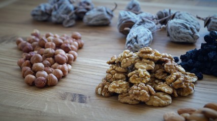 dried fruit mix of dried persimmon, raisins and different varieties of nuts on a wooden table