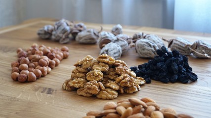 dried fruit mix of dried persimmon, raisins and different varieties of nuts on a wooden table