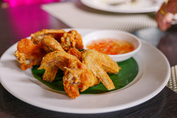 Thai style deep fried crispy chicken wing, serve on white dish with spicy sweet sauce on side. Thai famous appetizer dish. 