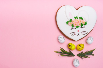 Easter bunny, gingerbread with glaze with quail eggs on pink background Copy space
