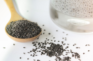 Raw basil seeds and sweet drink in glass on white background.