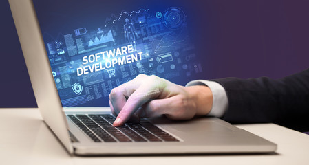 Businessman working on laptop with SOFTWARE DEVELOPMENT inscription, cyber technology concept