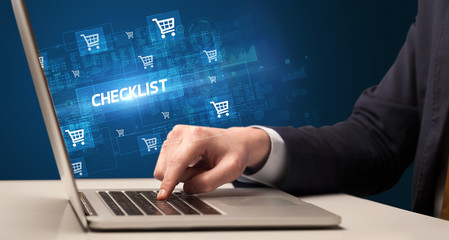 Businessman working on laptop with CHECKLIST inscription, online shopping concept