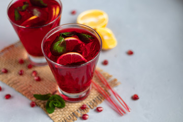 Pomegranate juice in transparent glasses. On a light background under a stone. Trend 2020. Grains are scattered nearby.