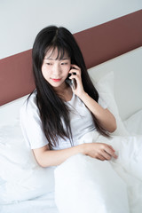 asian young woman making phone call on bed