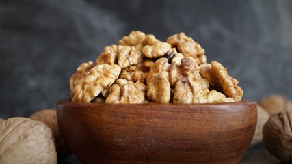 walnut kernels in a wooden dish on a black background