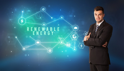 Businessman in front of cloud service icons with RENEWABLE ENERGY inscription, modern technology concept