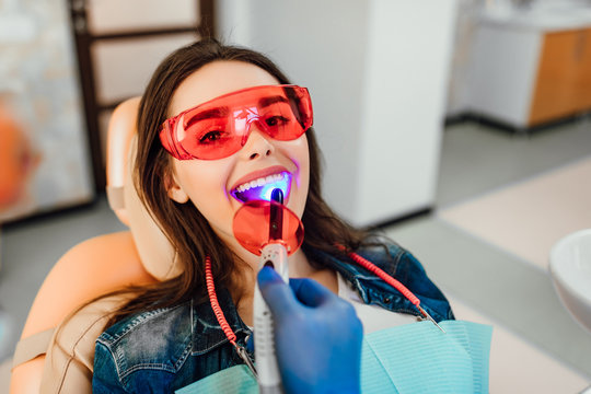 Dentist ultraviolet light checking up the teeth of a young caucasian woman.