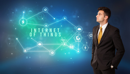 Businessman in front of cloud service icons with INTERNET OF THINGS inscription, modern technology concept