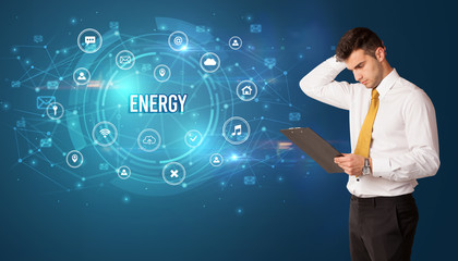 Businessman thinking in front of technology related icons and ENERGY inscription, modern technology concept