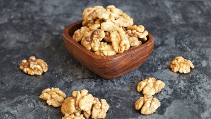 walnut kernels in a wooden dish on a black background