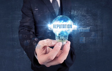 Businessman holding a light bulb with REPUTATION inscription, new business concept
