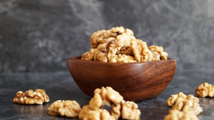 walnut kernels in a wooden dish on a black background