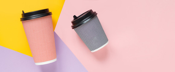 paper coffee cups lie on a bright pink background with a yellow lilac with a place for the inscription close up flat lay