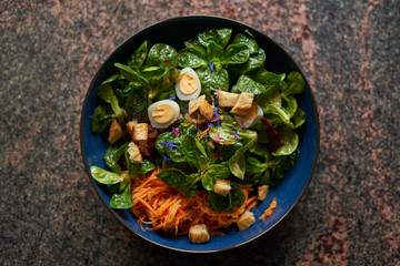Feldsalat mit Karotten und Wachteleiern angerichtet in königsblauer Keramik