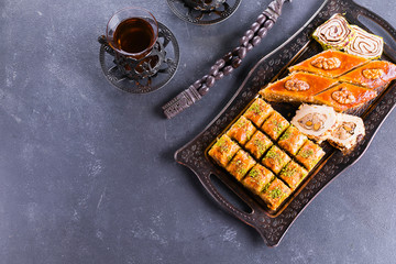 Baklava. Ramadan Dessert. Assortment of Arabic dessert with nuts and honey, cups of tea on a concrete table. Top view, copy space