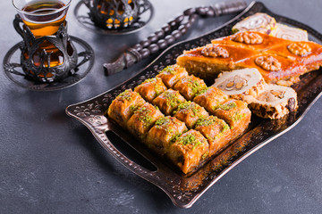Assortment of oriental sweets. Baklava and two cups of tea on a blue concrete table. Close-up image