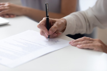 Close up view female hand signing contract legal document