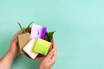 Woman hands holding natural organic color soap bar on blue background. Healthy lifestyle, beauty, skin care. Zero waste home concept.