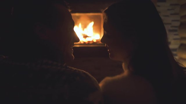 The smiling couple sitting by the fireplace